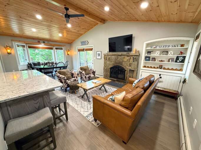 Unwind on the leather sofa after a day outdoors, with the stone fireplace and TV at the center of the room.