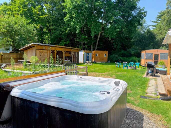 The back yard offers a private area to relax with a hot tub, fire pit, grill, and seating. The back yard offers a private area to relax with a hot tub, fire pit, grill, and seating.