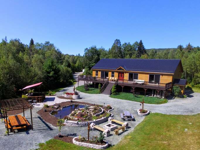 The front yard features a pond with waterfalls, firepit, outdoor kitchen, huge outdoor table with pergola (plus an additional table and shade pergola on the deck), lawns for playing, and more!