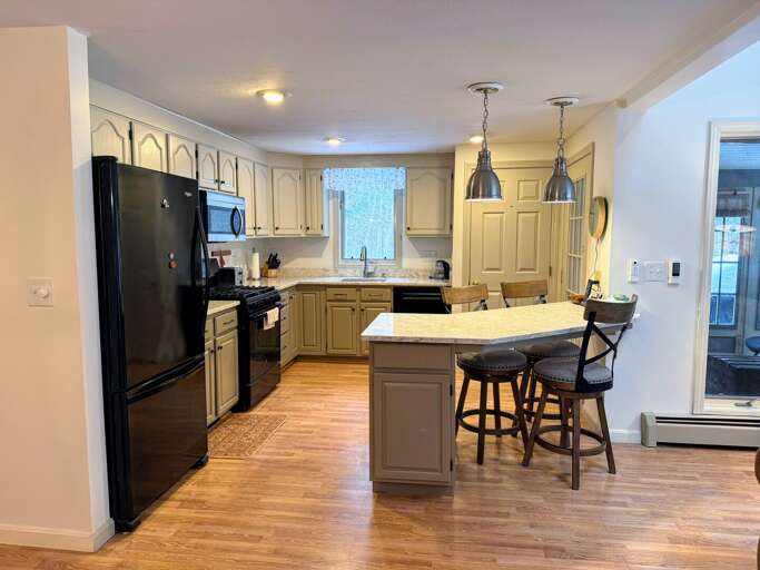 Large kitchen area with standard appliances, a pantry, breakfast bar, and access to the screened porch.