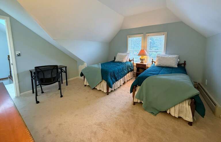 The Upper Level Twin bedroom offers two twin beds, a dresser and closet, and a desk.