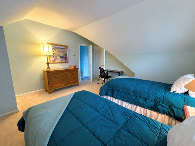 The Upper Level Twin bedroom offers two twin beds, a dresser and closet, and a desk.