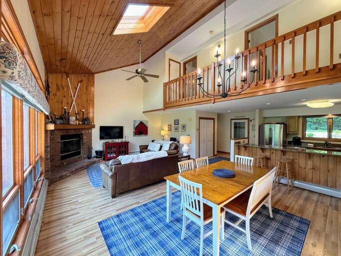Main Level Living room offers comfortable seating, a wood burning fireplace, and TV. It's in an open-concept main area adjacent to the dining room and kitchen.