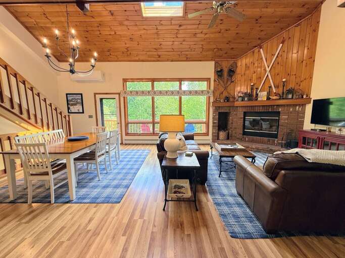 Main Level Living room offers comfortable seating, a wood burning fireplace, and TV. It's in an open-concept main area adjacent to the dining room and kitchen.