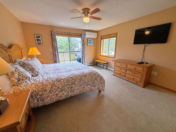 Primary bedroom with King bed, TV, walkout slider, and ensuite bath.