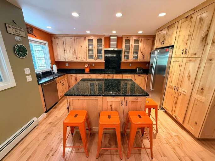 Kitchen with granite countertops, stainless steel appliances, and large island with breakfast bar.