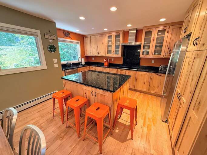 Kitchen with granite countertops, stainless steel appliances, and large island with breakfast bar.
