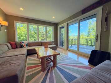 Main level living area adjacent to dining area with walkout slider to main level deck and mountain views.
