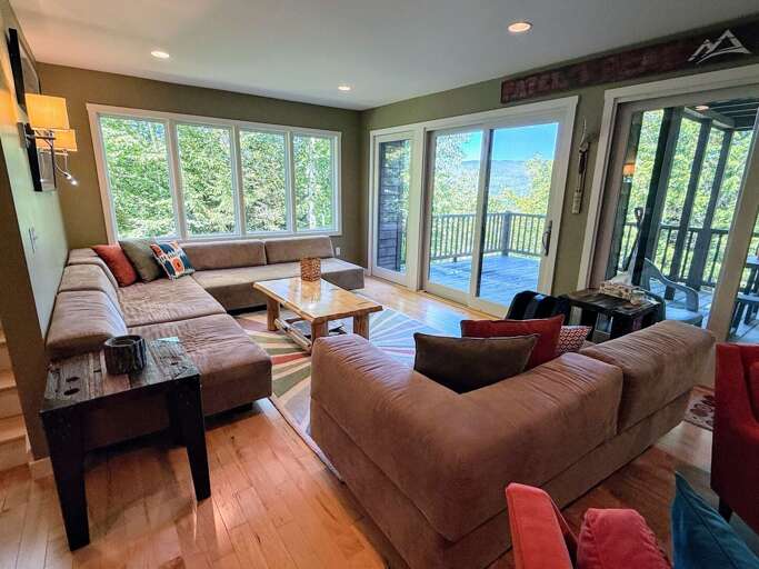 Main level living area adjacent to dining area with walkout slider to main level deck and mountain views.