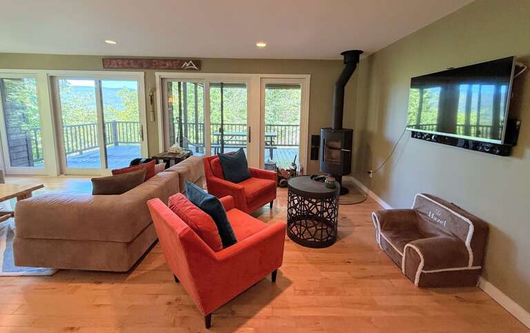 Main level living area with wood burning fireplace and TV and walkout access to outdoor table and mountain views.