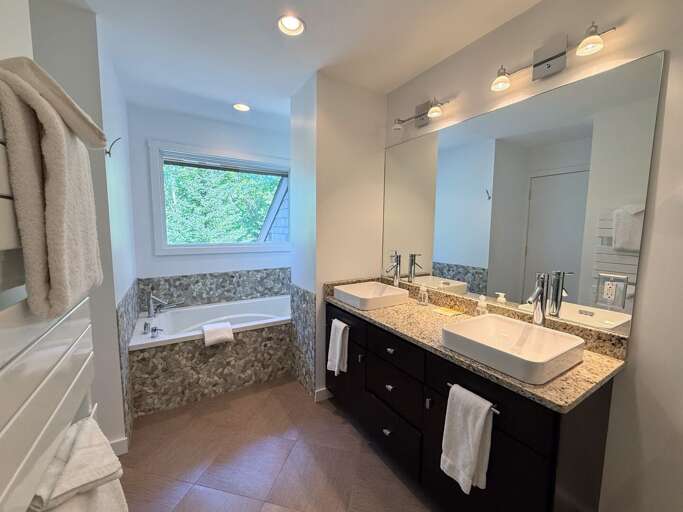 Upper level king bedroom ensuite bathroom with double vanity, custom shower and soaking tub.