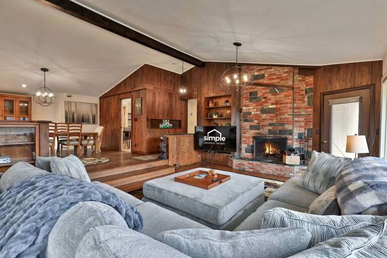 Living space with warm, cabin-like aesthetic under vaulted ceilings. It features a brick and stone