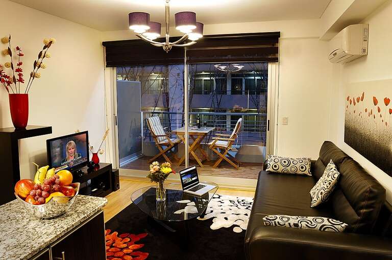 This contemporary flat provides a cozy living area adorned in pleasant hues. It boasts a comfortable sofa, a workspace complete with laptop, and sliding doors that open onto your own private balcony.