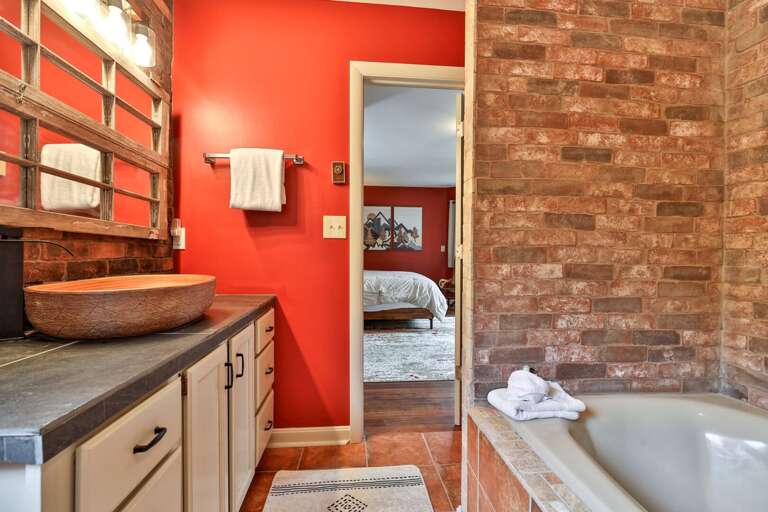 Full bathroom with red accents and brick details. Stylish and spacious enough for the morning routine.