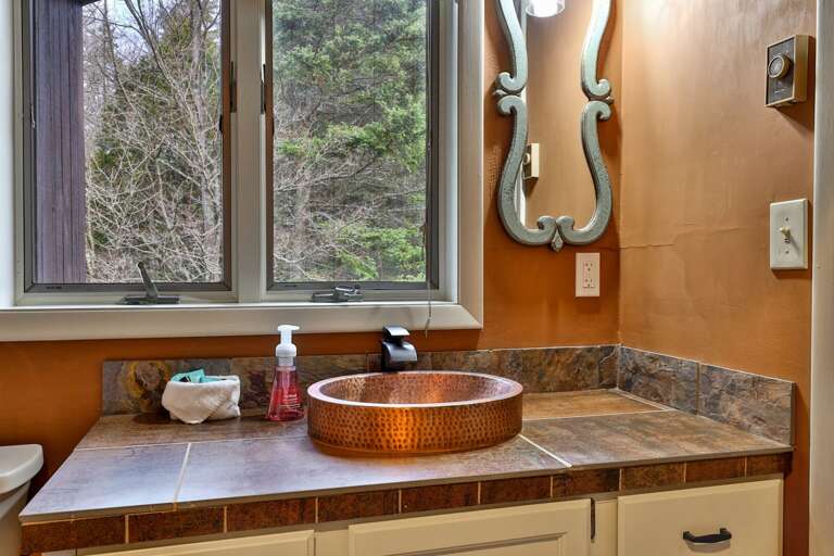 Hammered copper vessel sink and forest views in the bathroom. Start your day connected to the Vermont outdoors.