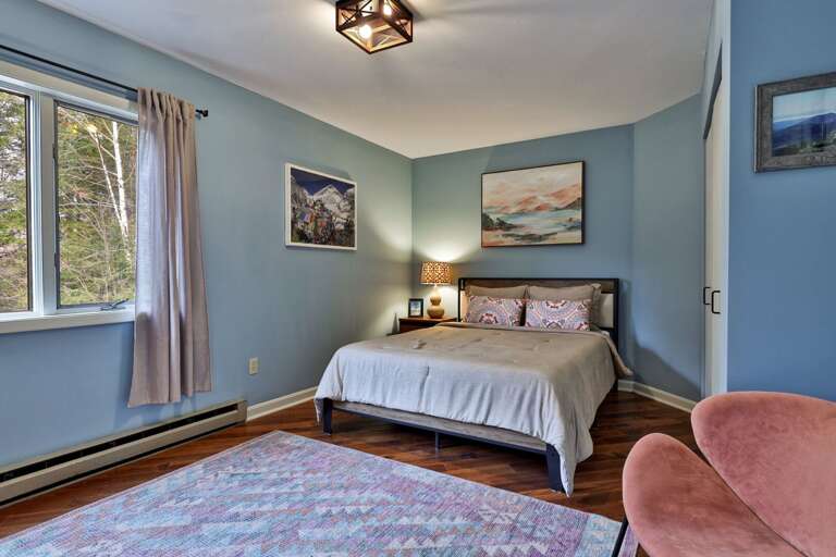 Peaceful blue bedroom with a queen bed and geometric rug. A quiet corner to recharge after hiking the Killington trails.