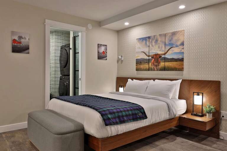 A comfortable queen bed with bedside lighting. In-unit laundry is tucked away for your convenience.