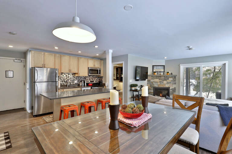 On the other side of the main suite is the open kitchen, a kitchen island with seating for four, and a high-top dining table with seating for six.