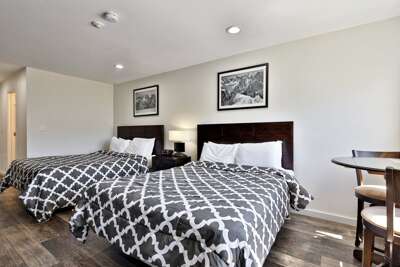 Renovated hotel-style Vermont studio featuring two queen beds with plush bedding and tasteful decorations.