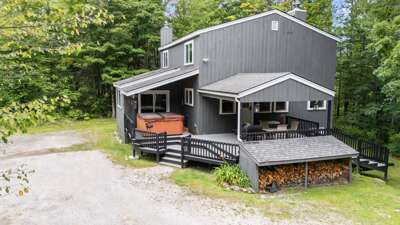 The forest-framed exterior shows off the broad decks and covered hot tub before you step inside.