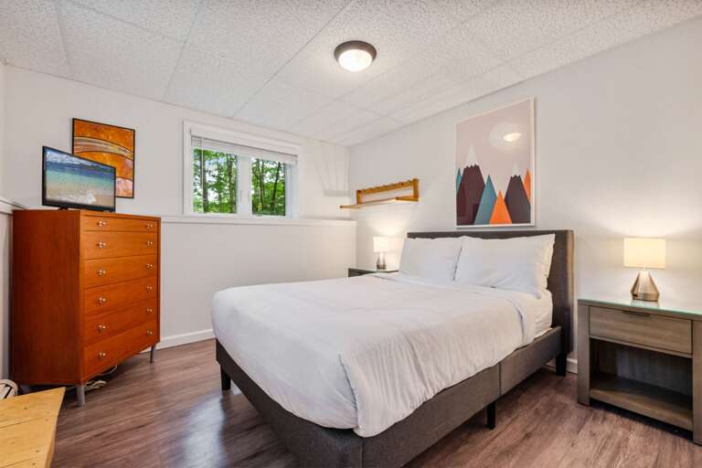 This lower-level bedroom keeps a dresser and TV directly across from the bed.