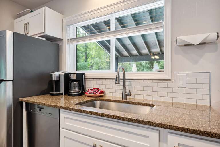 Morning coffee starts beside the sink, with a leafy view over the covered deck.
