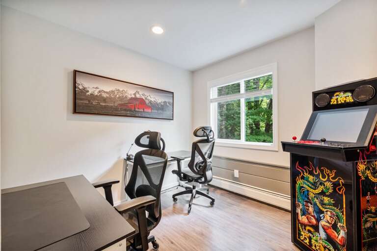 Two side-by-side desks handle remote work or trip planning, and the arcade cabinet is ready for a break.
