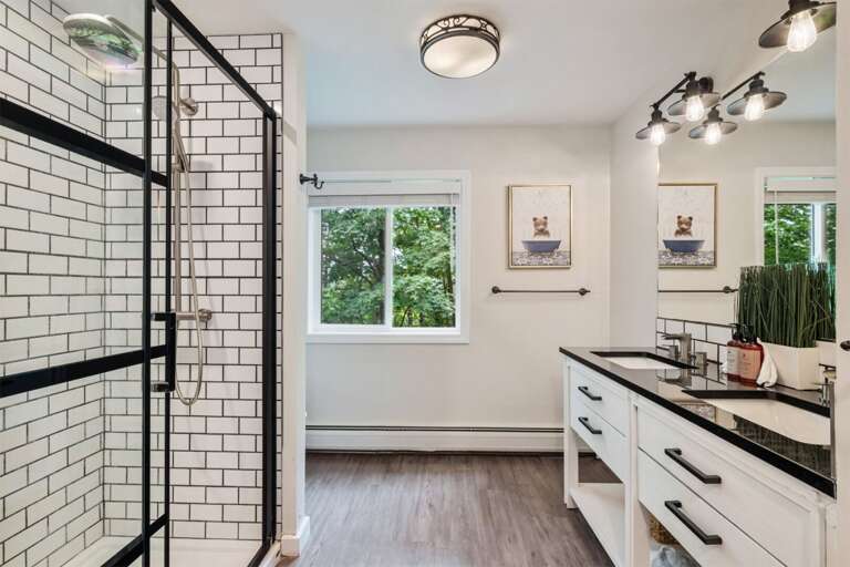 Two sinks let guests get ready together, with the walk-in shower beside them.