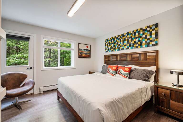 Windows on two sides bring the forest into view from this spacious bedroom.
