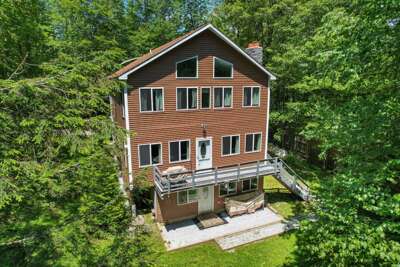 Three-story home surrounded by trees, with Vermont sunshine streaming through the many windows.