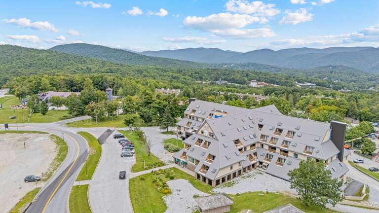 The aerial view shows the lodge in the foreground with Killington's wooded peaks stretching behind it.