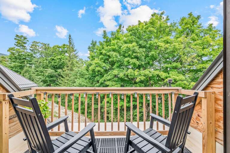 Two chairs wait on the private balcony for coffee, fresh air, and a quiet look into the trees.