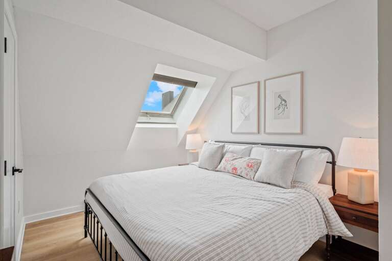 The main bedroom pairs a comfortable king bed with morning light from the skylight and lamps on both sides.