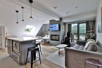 Cozy studio condo featuring a fully-equipped kitchen with a Keurig machine, a private balcony with mountain views, and an inviting living space with an electric fireplace and smart TV.