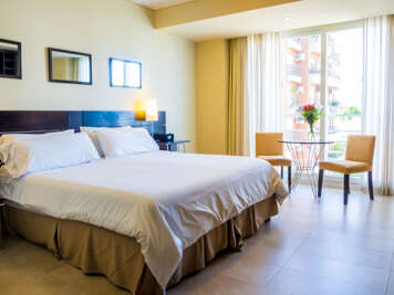 Our cozy Buenos Aires studio features a king bed, that can be split into two upon request, and a dining table next to its large French-balcony window.