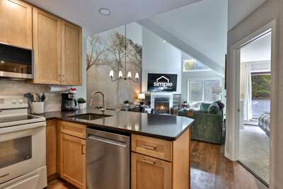 The condo's cozy open loft and wood-burning fireplace seen from its renovated kitchen.