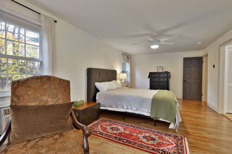 Bedroom With Bed, Chair, Dresser, Window, And Rug
