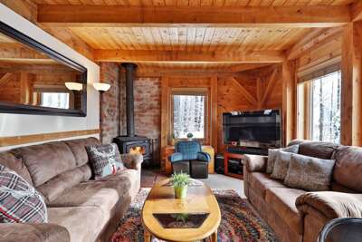 Tastefully-decorated living room with color accents combining with wood. Wood-burning stove, comfy sofas and a smart TV with streaming services to socialize and relax after a day of adventure.