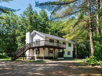 The Output Double is a scenic, two-story house nestled in a lush, wooded environment, with an elevated deck. (This listing is for its lower unit.)