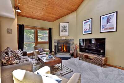 The living room of our charming Trail Creek condo at Killington Resort features a sleeper sofa, a smart TV, a wood-burning fireplace, and a small balcony to enjoy the mountain air.