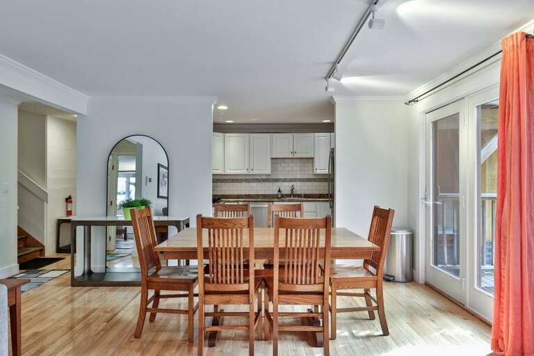 Linger at the dining table over breakfast, with the kitchen behind you and daylight through the deck doors.