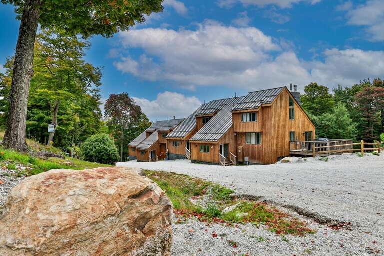 The wood-sided condo buildings sit along a gravel approach, surrounded by trees beginning to turn for fall.