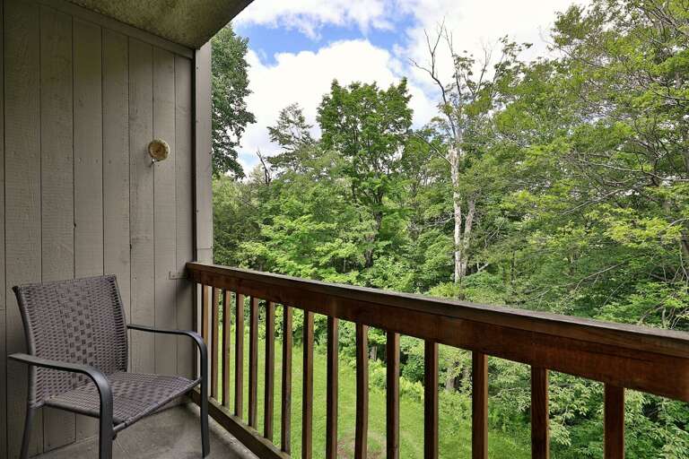 Experience the tranquility of nature from our balcony, complete with comfy chairs, boasting stunning views over a lush wooded area.