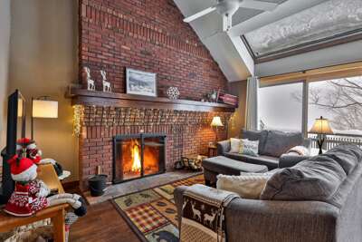 The living room has a large sectional sofa, a smart TV, and a wood-burning fireplace.