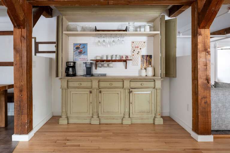 Built-in beverage station with a coffee maker, open shelving, glassware storage, and cabinet space.