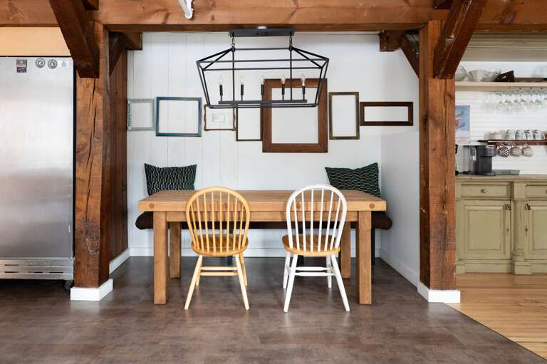 Dining nook beside the kitchen with table seating beneath exposed timber beams.