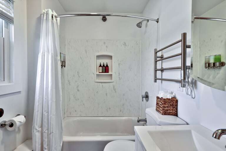 This full bathroom includes a tub, overhead shower, and room to keep towels close by.