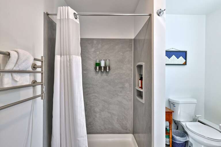 A glass-front walk-in shower and heated towel rack keep the bathroom simple and functional.