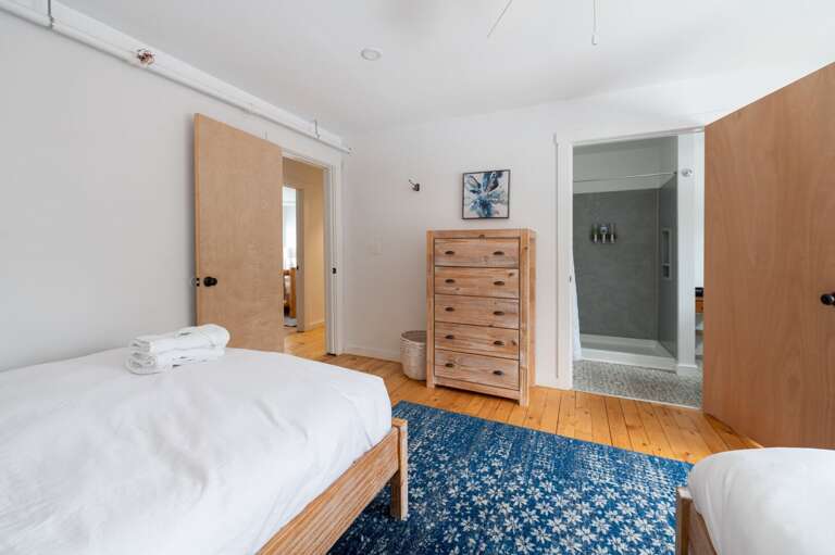 Guest bedroom with two beds, dresser, ceiling fan, and direct access to a bathroom.