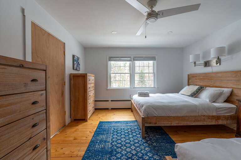 Guest bedroom with two beds, dressers, a ceiling fan, and a wide window.
